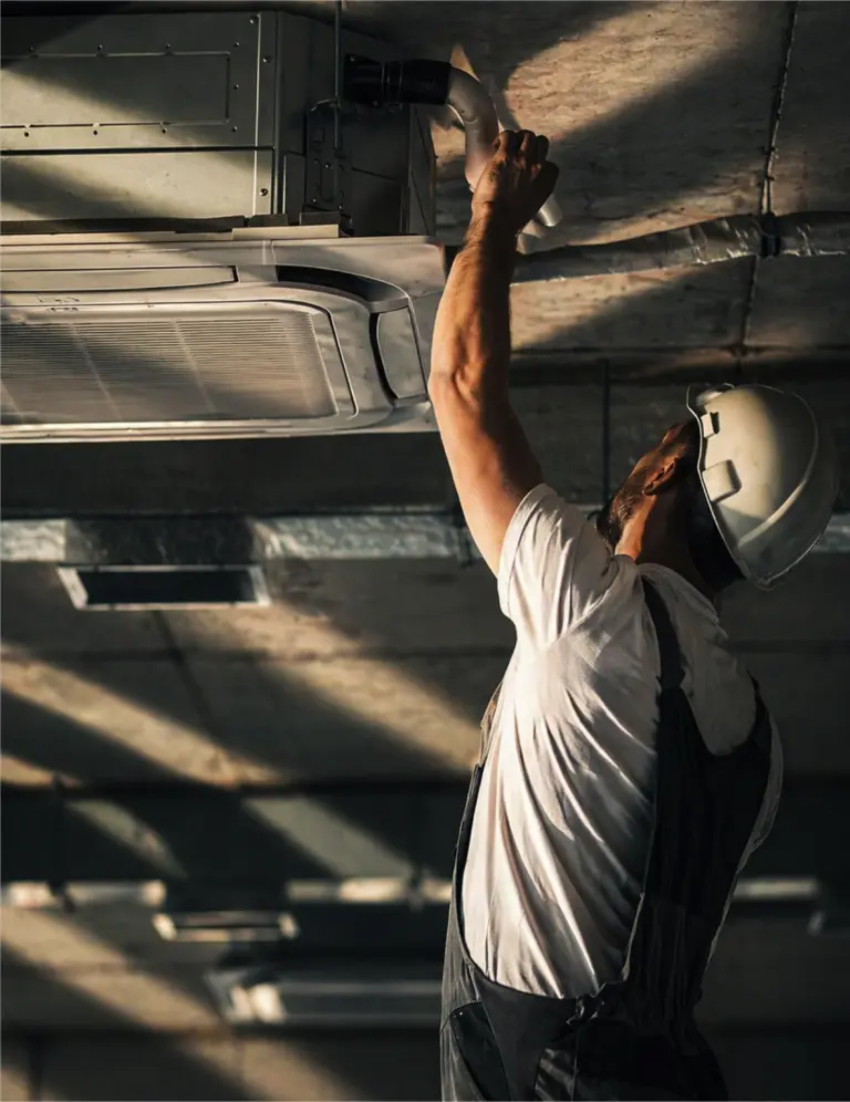 Technicien installant un système de ventilation au plafond.