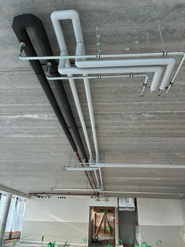 Isolation des tuyaux au plafond pour l'immeuble de bureaux sans énergie fossile Semlex à Drogenbos.