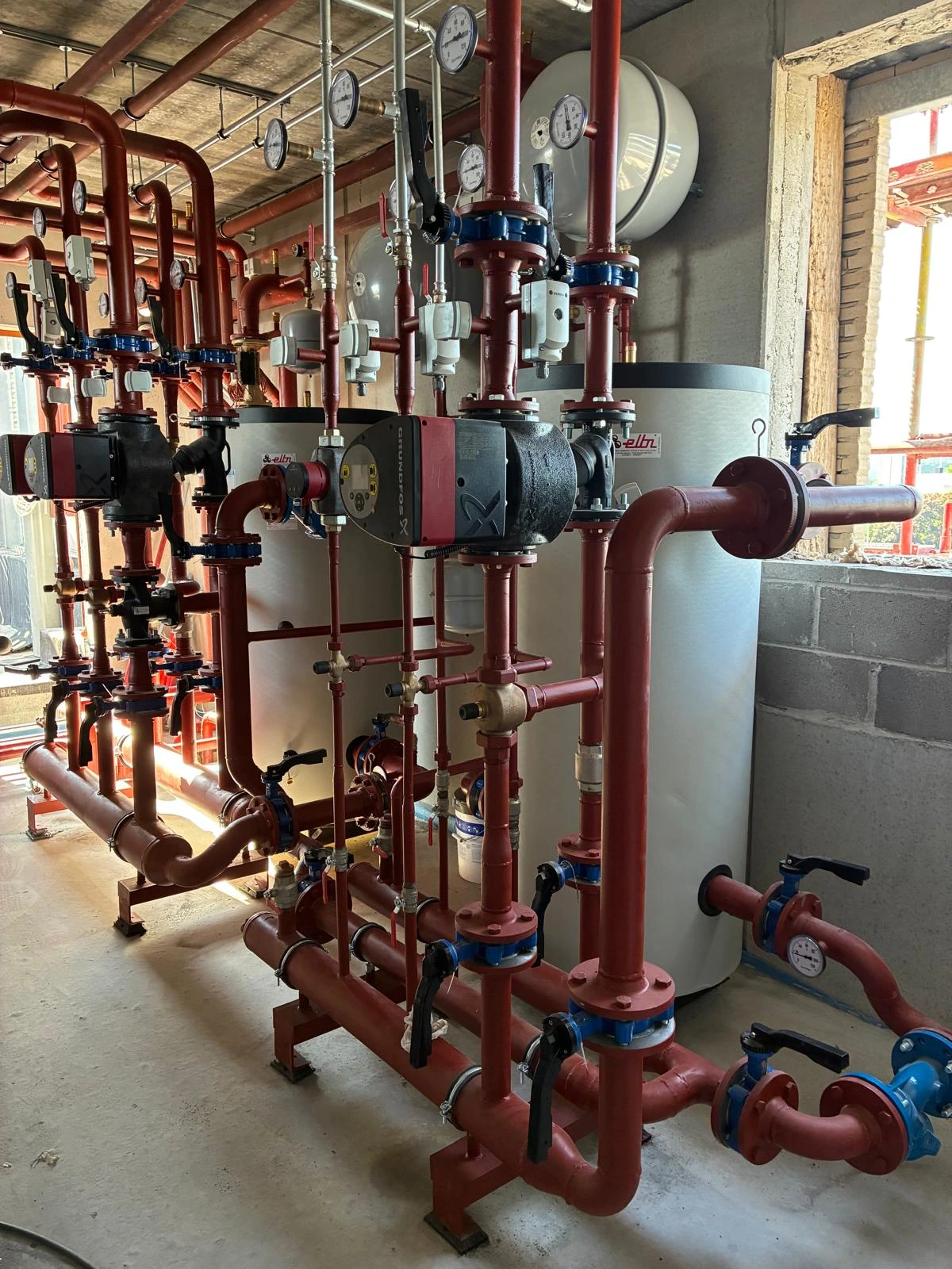 Installation du système CVC durable avec tuyaux rouges et ballons d'eau pour les bureaux Semlex à Drogenbos.