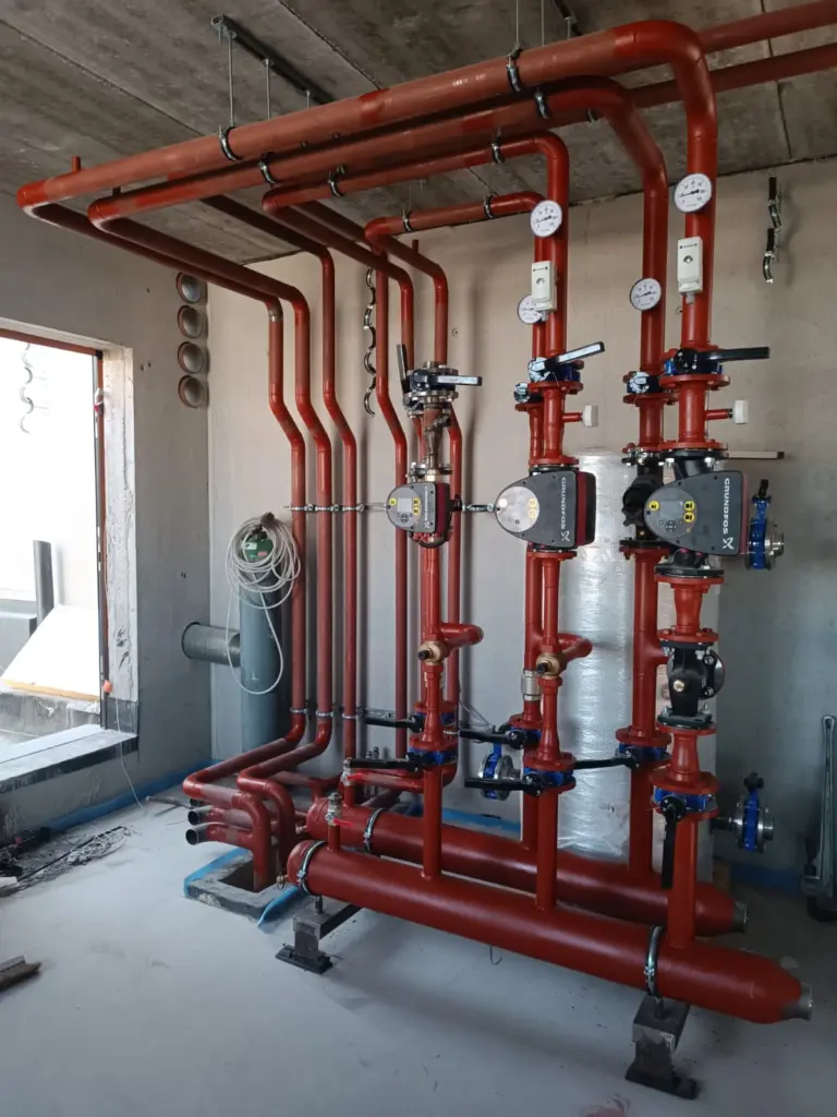 Pompes Grundfos et tuyauterie CVC rouge pour les bureaux écoénergétiques Semlex à Drogenbos.